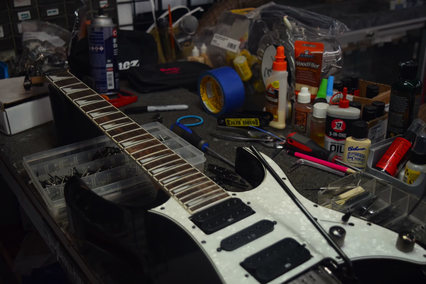An electric guitar disassembled on the repair bench at Musicians Discount Center, surrounded by luthier tools and supplies